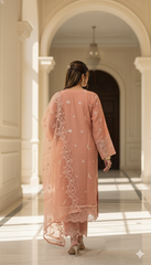 Woman in a pink traditional outfit standing in a sunlit hallway with arched doorways.